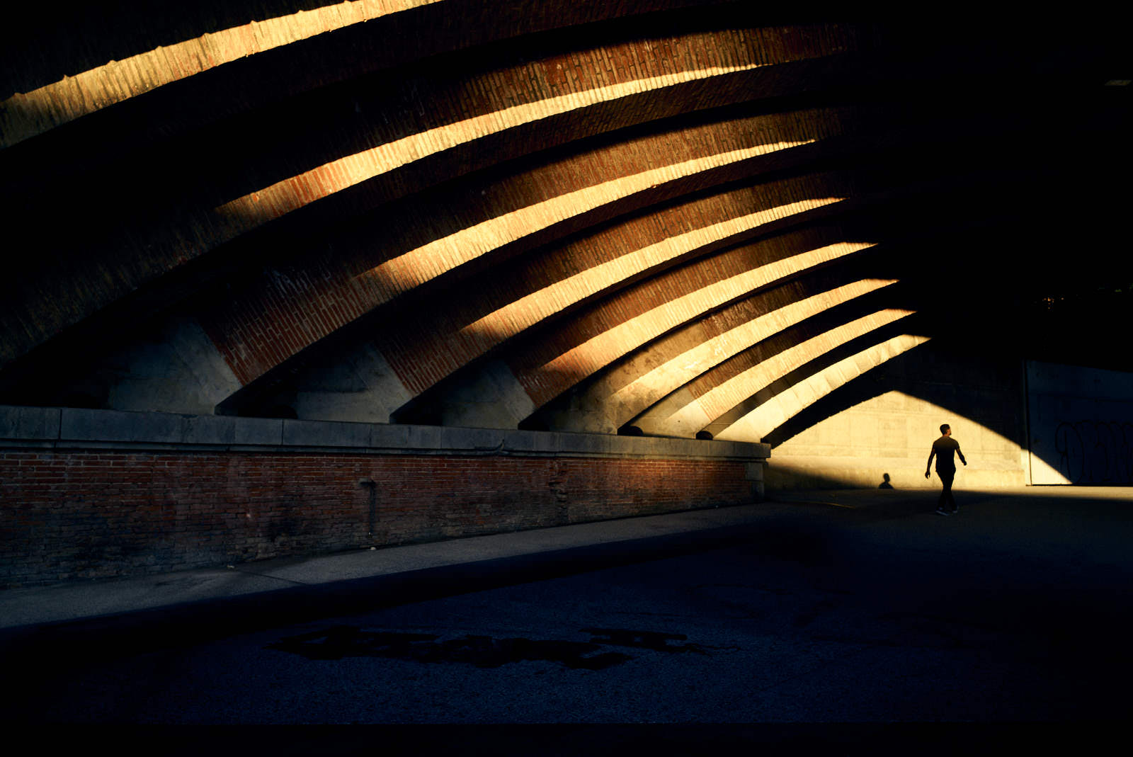 man passing under a bridge with light from sunset in toulouse