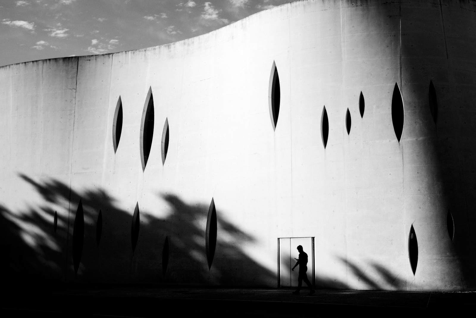 silhouette in front of a building with shadows from trees