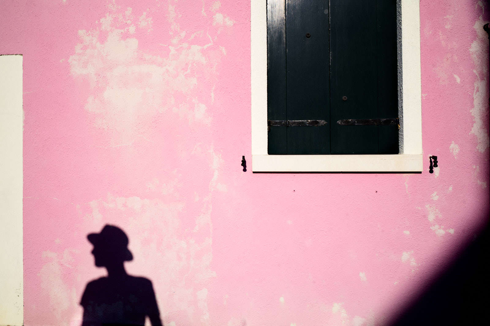 shadow of a man on a pink wall in burano venice italy